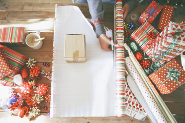 Frau schneidet Geschenkpapier für Weihnachtsgeschenke - RTBF00425