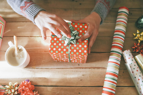 Woman's hands placing tie on Christmas gift stock photo