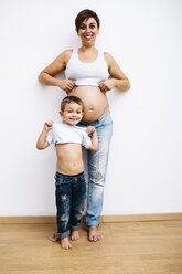 Kleiner Junge und schwangere Mutter heben ihre T-Shirts hoch - JRFF00907
