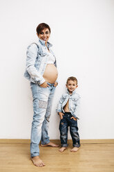 Schwangere Mutter und kleiner Sohn stehen mit den Händen in den Taschen - JRFF00908