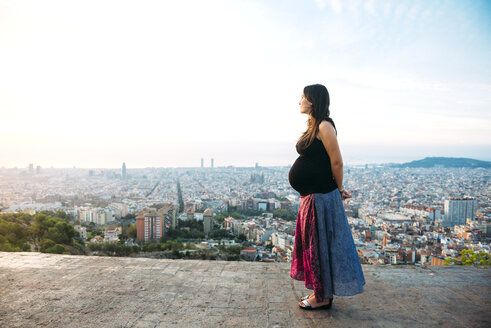 Spanien, Barcelona, Schwangere Frau genießt den Blick über die Stadt - GEMF01128