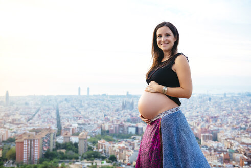 Spanien, Barcelona, Schwangere Frau genießt den Blick über die Stadt - GEMF01135