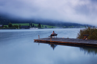 Austria, Carinthia, Man sitting on jetty at Lake Weissensee - GFF00784