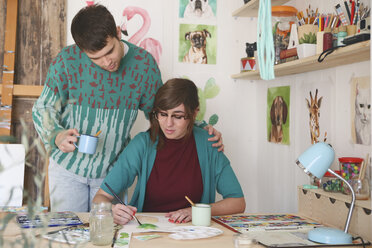 Artist painting in her studio while her boyfriend watching her - RTBF00437