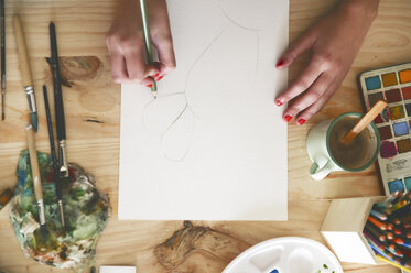 Frauenhand zeichnet einen Kaktus mit grünem Bleistift auf Papier - RTBF00442