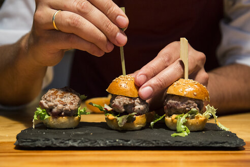 Mann steckt einen Spieß in einen Mini-Burger mit rotem Thunfisch - ABZF01367