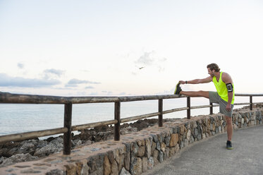 Spanien, Mallorca, Jogger streckt Bein - DIGF01352