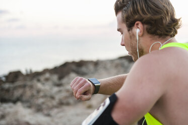 Spanien, Mallorca, Jogger am Strand, Blick auf Smartwatch - DIGF01355