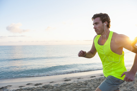 Spanien, Mallorca, Jogger mit Kopfhörern am Strand am Morgen, lizenzfreies Stockfoto