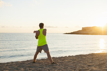 Spanien, Mallorca, Jogger am Strand am Morgen, Stretching - DIGF01364