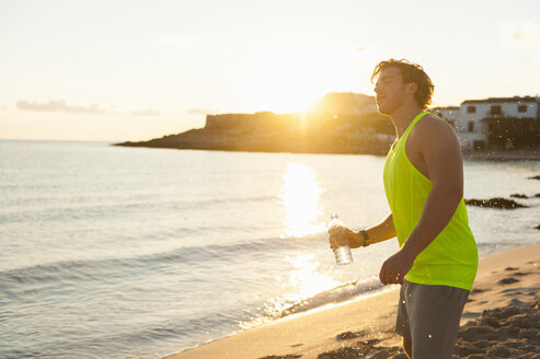 Spain, Mallorca, Jogger with water bottle at the beach - DIGF01366