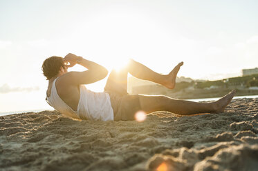 Spanien, Mallorca, Jogger am Strand bei Sonnenaufgang, Situps - DIGF01373