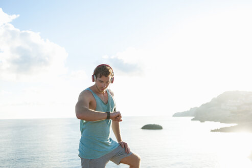 Spanien, Mallorca, Jogger schaut auf Smartwatch - DIGF01384