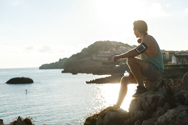 Spain, Mallorca, Jogger with water bottle at the beach - DIGF01393