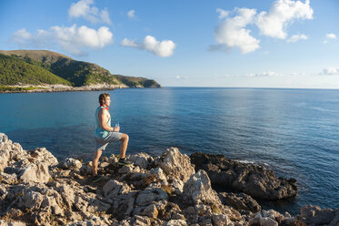 Spain, Mallorca, Sportsman standing on rocky coast in the morning - DIGF01396