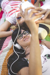 Young woman with friends lying on blanket listening to music - DAPF00367