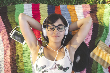 Relaxed young woman lying on blanket listening to music - DAPF00372