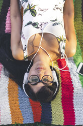 Young woman lying on blanket listening to music - DAPF00373