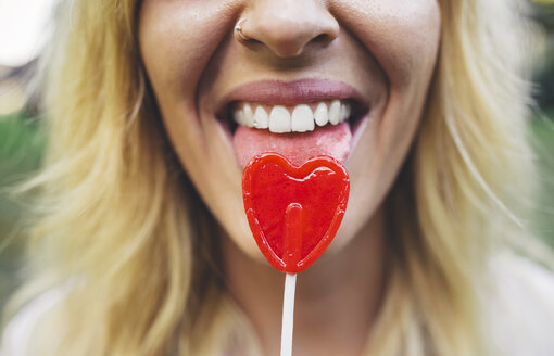 Close-up of young woman licking heart-shaped lollipop - DAPF00399