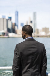 USA, Brooklyn, back view of businessman looking at skyline of Manhattan - GIOF01471