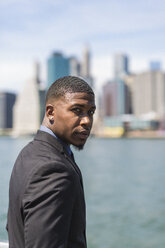 USA, Brooklyn, portrait of businessman in front of Manhattan skyline - GIOF01473