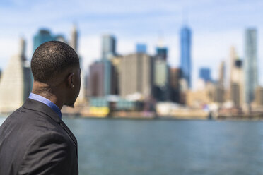 USA, Brooklyn, Rückenansicht eines Geschäftsmannes mit Blick auf die Skyline von Manhattan - GIOF01475