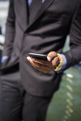 Hand of businessman holding cell phone, close-up - GIOF01477