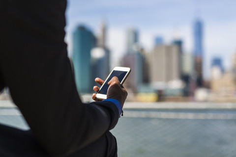 USA, Brooklyn, Hand eines Geschäftsmannes, der ein Mobiltelefon hält, lizenzfreies Stockfoto