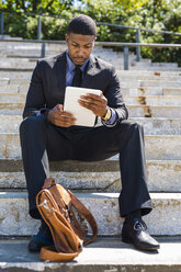 Geschäftsmann sitzt auf einer Treppe und benutzt ein Tablet - GIOF01494