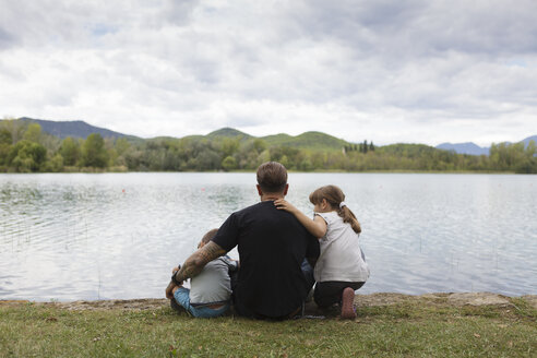 Rückenansicht eines Mannes, der mit seinen Kindern am Seeufer sitzt - XCF00107