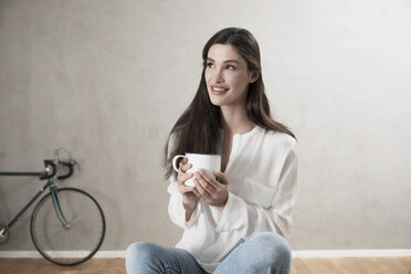 Portrait of smiling woman relaxing with cup of coffee - FMKF03095