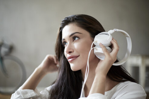 Lächelnde Frau mit weißen Kopfhörern hört Musik - FMKF03097