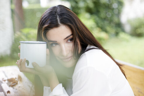 Portrait of smiling woman relaxing with cup of coffee - FMKF03099