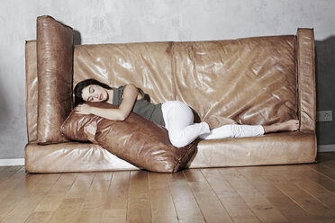 Woman relaxing on upset leather couch - FMKF03125