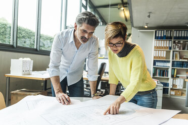 Male and female architects discussing ground plan in office - TCF05139