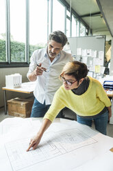 Männliche und weibliche Architekten besprechen einen Grundriss im Büro - TCF05140