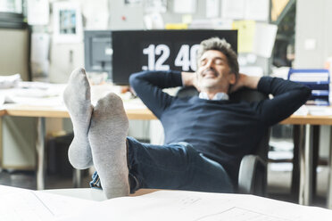 Mature man sitting at his desk with feet up - TCF05166