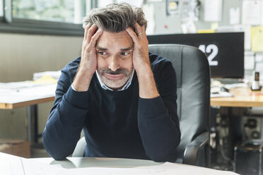 Mature man sitting in office with head in hands - TCF05167