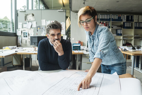 Männliche und weibliche Architekten besprechen einen Grundriss im Büro - TCF05173