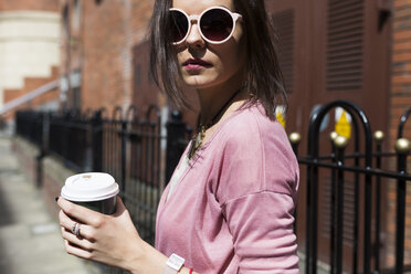 Fashionable young woman with coffee to go wearing pink sunglasses and cardigan - BOYF00591