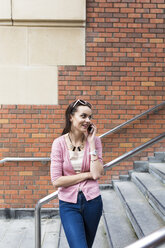 Woman standing on stairs telephoning with smartphone - BOYF00593