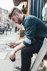 Junger Skateboarder schaut auf sein Handy - BOYF00601