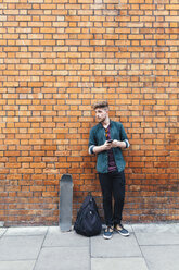 Junger Skateboarder vor einer Backsteinmauer stehend - BOYF00604