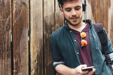 Young listening music with headphones while looking at cell phone - BOYF00610