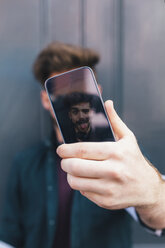 Display eines Smartphones mit einem jungen Mann, der seine Zunge herausstreckt - BOYF00626