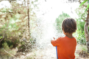 Back view of little boy playing with garden hose - VABF00813