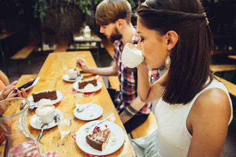 Freunde sitzen im Freien bei Kaffee und Kuchen, lizenzfreies Stockfoto