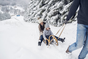 Glückliche Familie mit Schlitten in Winterlandschaft - HAPF00950