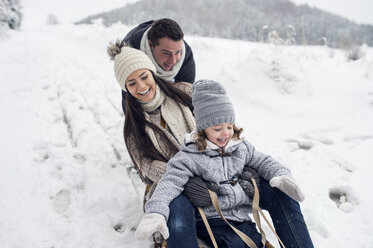 Glückliche Familie auf Schlitten in Winterlandschaft - HAPF00953