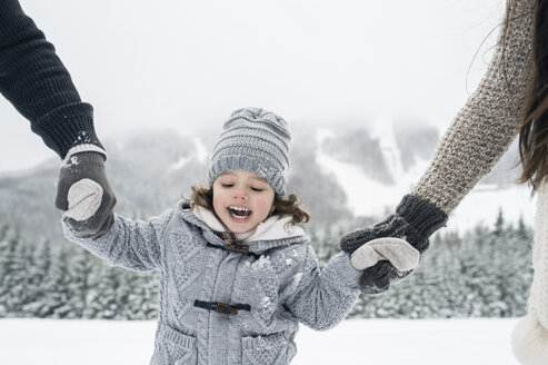 Glückliches Mädchen Hand in Hand mit Eltern in Winterlandschaft - HAPF00960